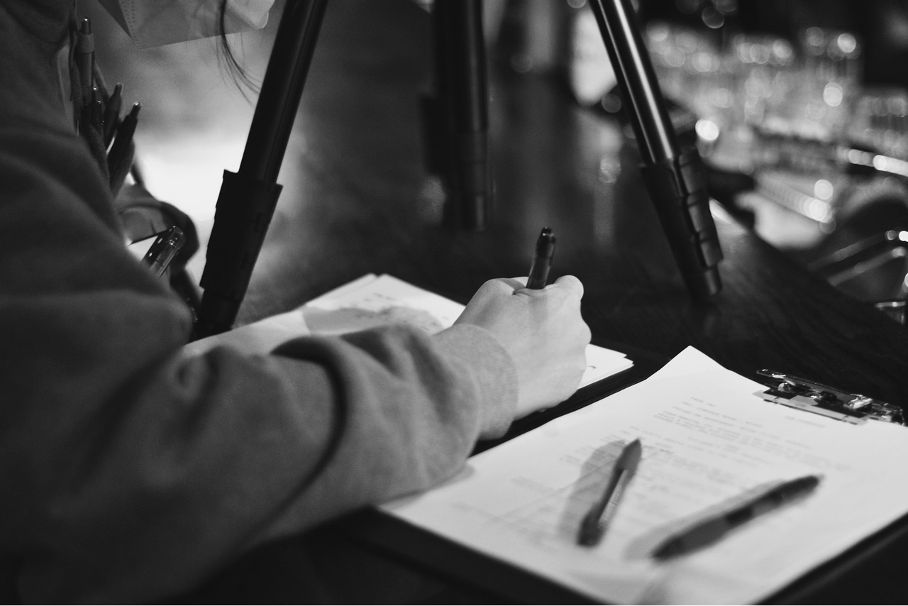 grayscale photo of man writing on paper